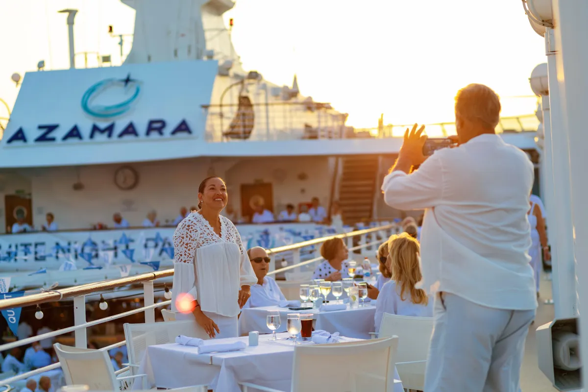 Guests dressed in white enjoy Azamara's signature White Night party on the open deck, surrounded by sunset views and elegant dining.