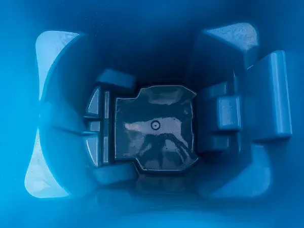 A top-down view inside a clean, empty blue plastic bin or recycling container.