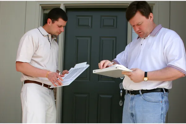 Home inspector and client standing at a doorway reviewing documents during an Orlando home inspection.