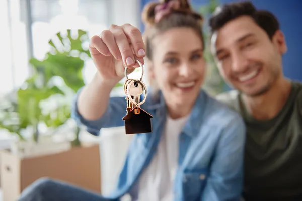 Smiling couple holding house keys inside their new home after a completed Orlando new construction inspection.