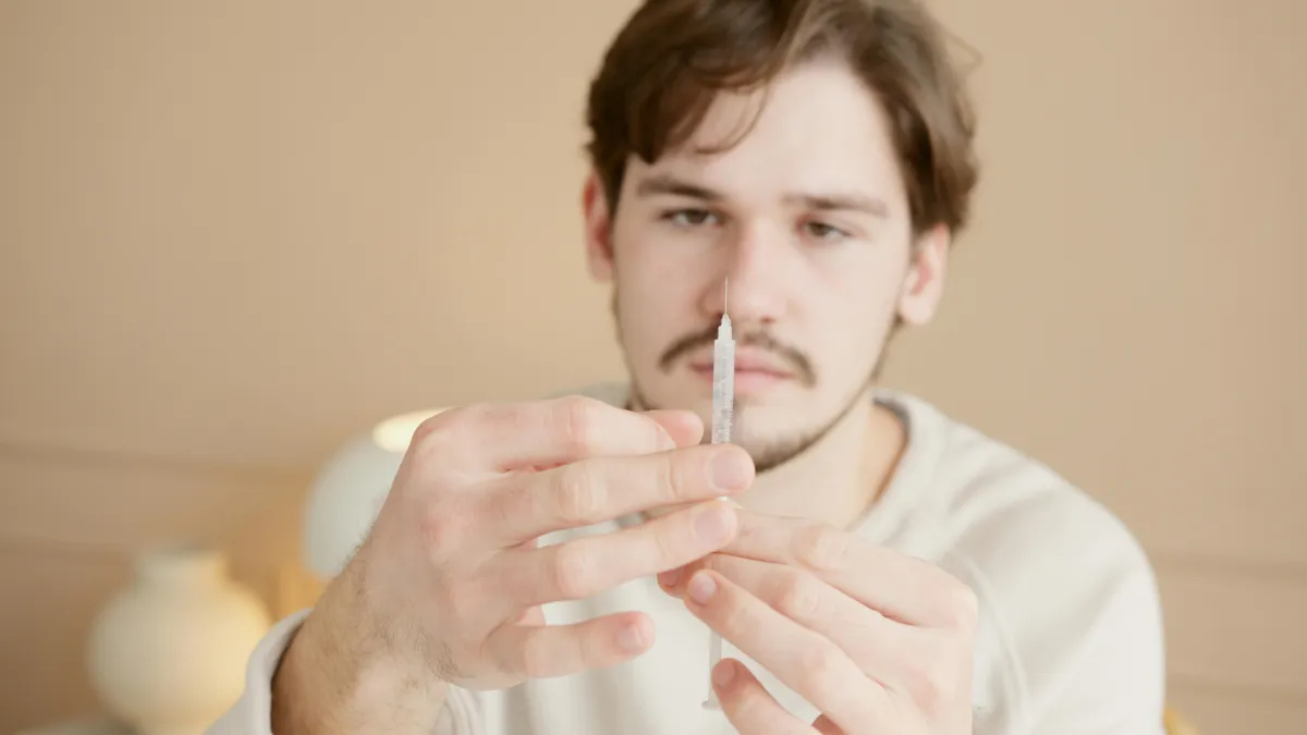 Man holding syringe – Hormone Replacement Therapy (HRT) helps restore testosterone, improve energy, sexual health, mood, and overall vitality at Hormone Treatment Centers in Overland Park, KS
