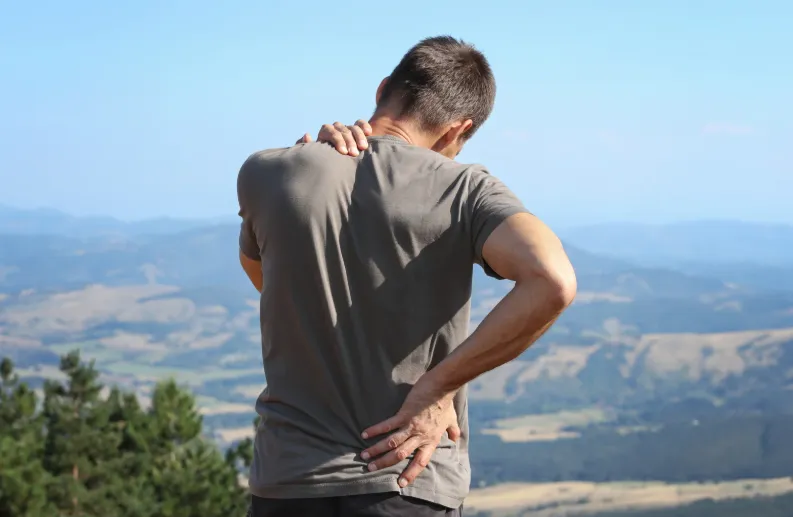 Overland Park man holding his back and neck in discomfort before testosterone therapy treatment for pain relief at Hormone Treatment Centers in Kansas.