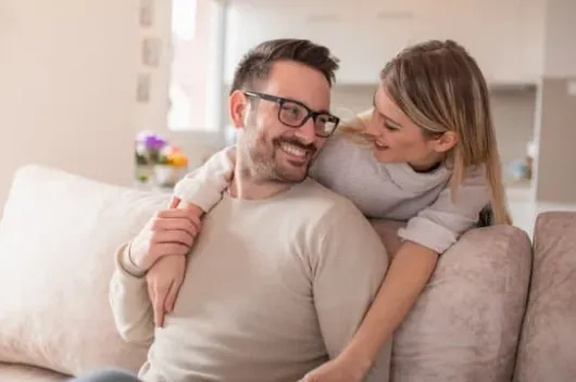 Smiling couple relaxing together at home after hormone replacement therapy from Hormone Treatment Centers of Kansas City, reflecting balance and improved well-being.