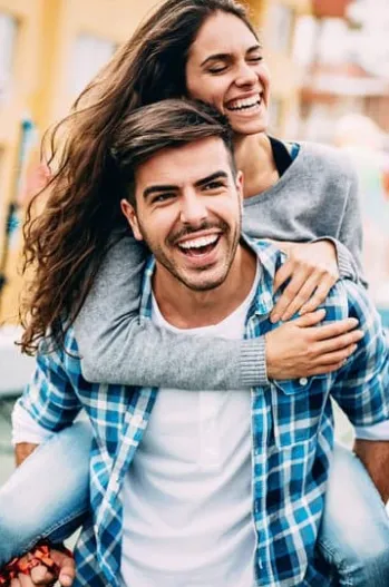 Happy couple laughing outdoors after hormone optimization therapy at Hormone Treatment Centers of Kansas City, symbolizing restored energy and balance.