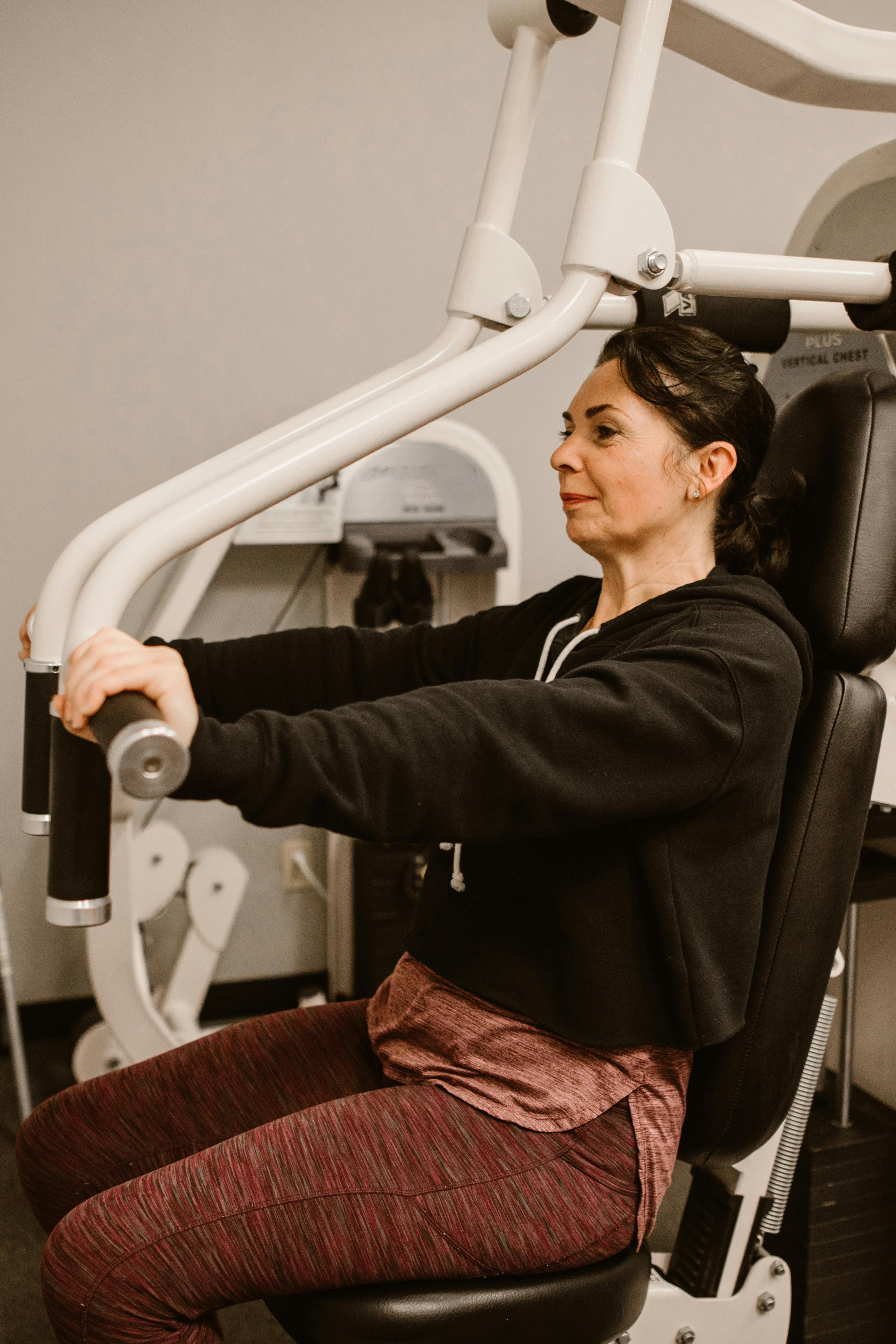 Woman strength training on a chest press machine, representing exercise recovery, mobility, strength, and wellness goals associated with BPC-157 peptide therapy.