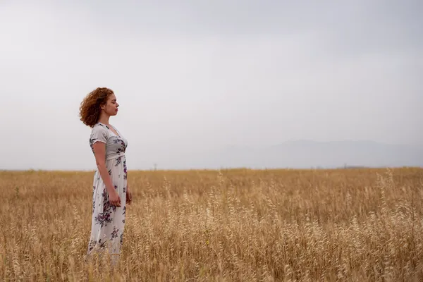 woman standing contemplating in a field