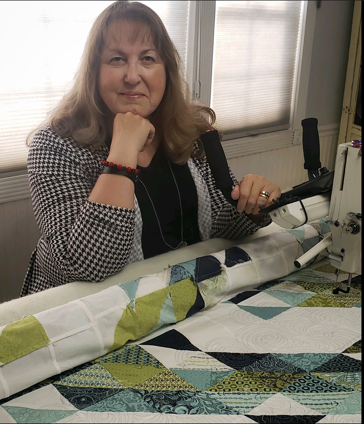 Darla happily working at her longarm quilting machine, creating intricate thread patterns