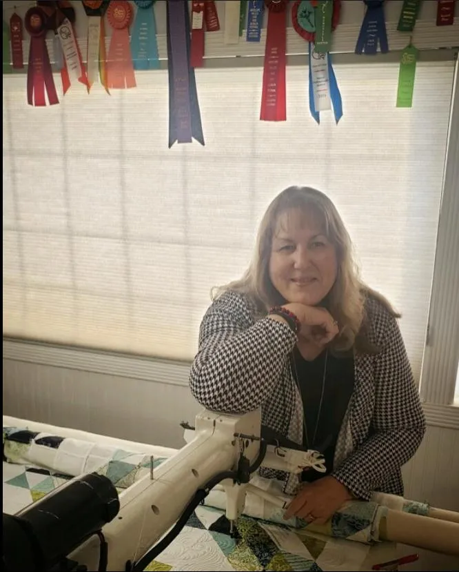 Darla happily working at her longarm quilting machine, creating intricate thread patterns