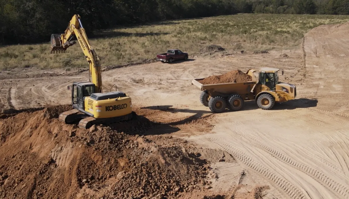 a large yellow truck driving down a dirt road