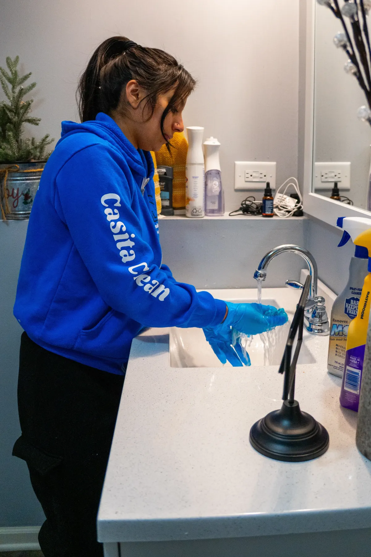 Casita Clean cleaner rinsing gloves at a bathroom sink during a routine clean in Naperville, IL
