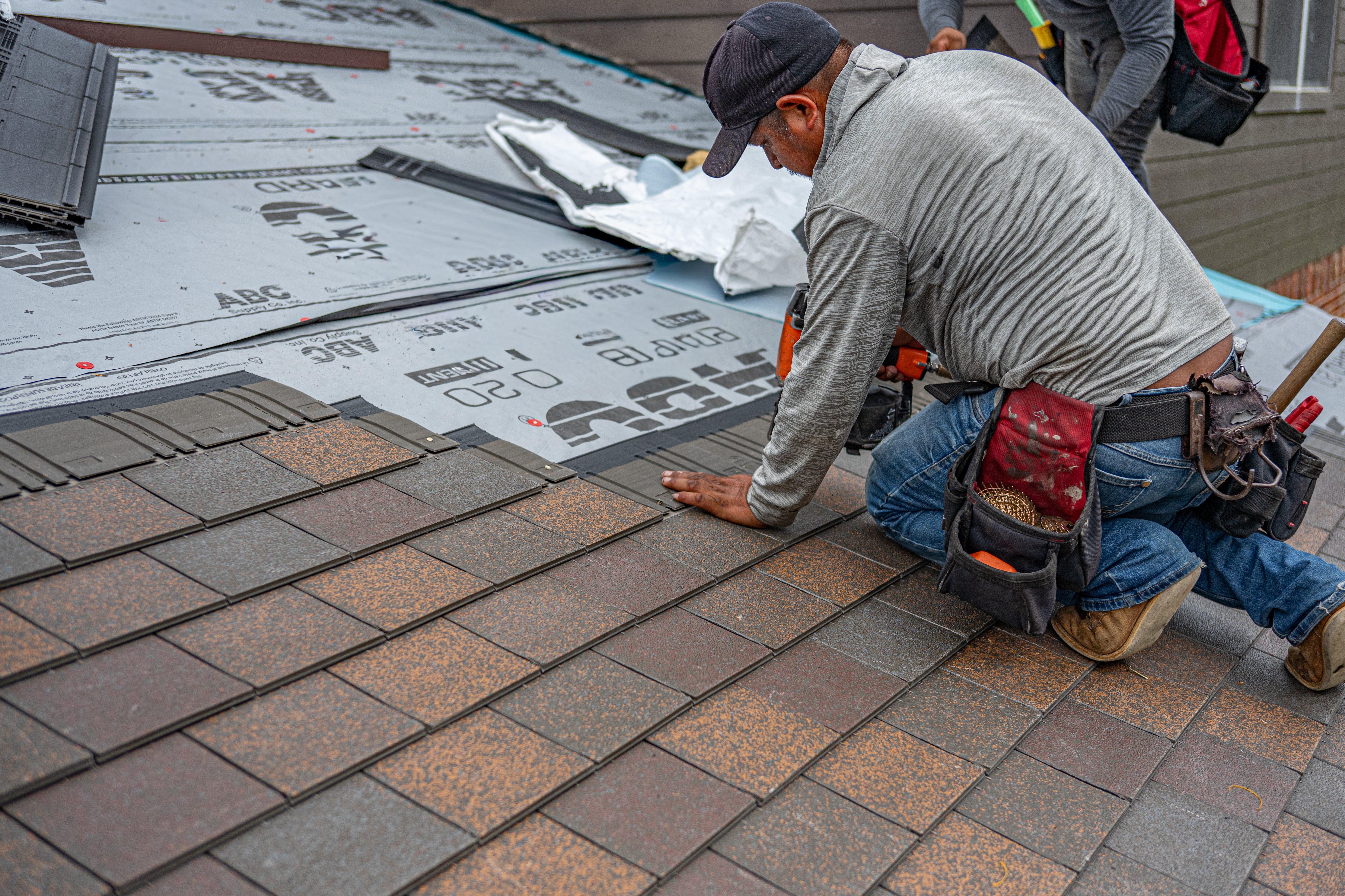 a roofer putting a new roof on the house using the nail gun