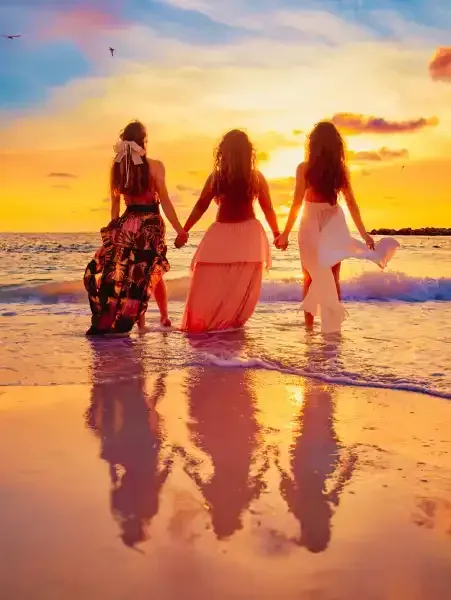 Lani Gonzales, in a red dress, embodies unlimited freedom and transformative healing for women at sunset.