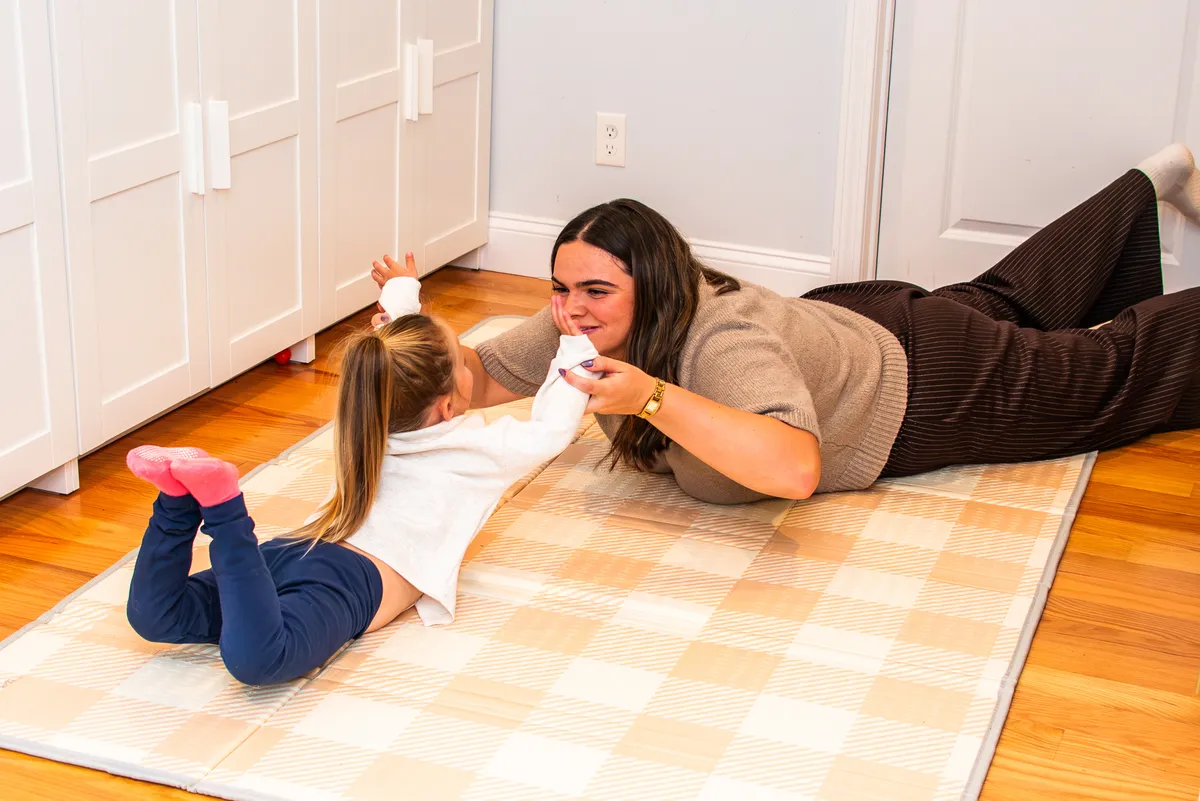 A pediatric occupational therapist helping a child with fine motor skills during a playful living room session