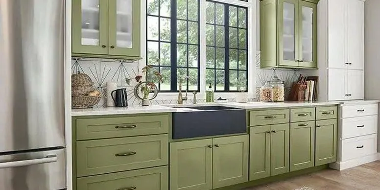Sage green kitchen cabinets with farmhouse sink, white countertops, and large window