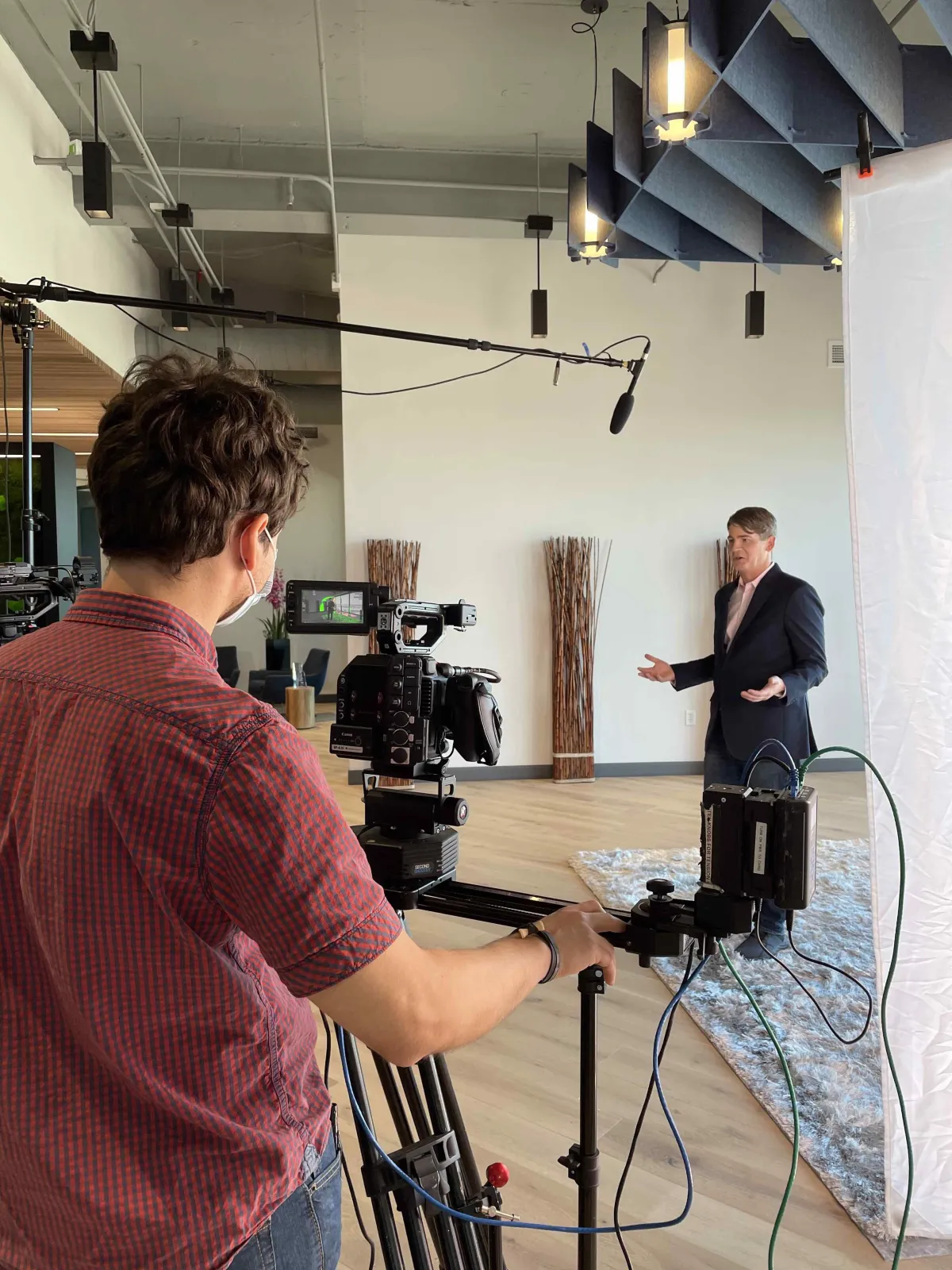 Video production of a customer testimonial with a man in a suit being interview by another man standing behind the professional camera