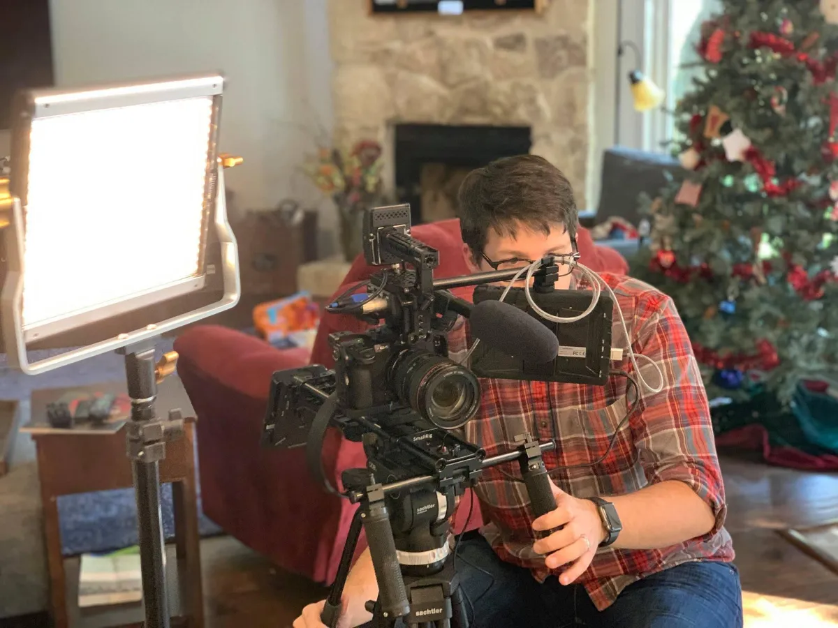 Jacob Forbis, owner of The Customer Story, behind video camera on corporate video shoot