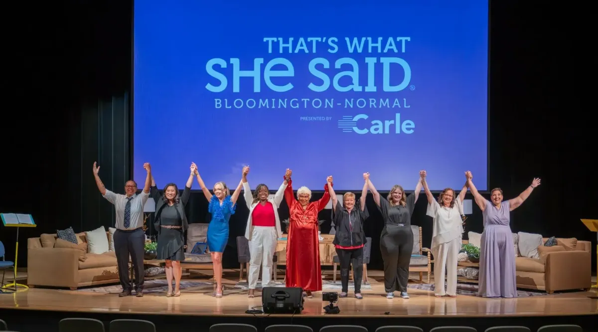 Image of a group of women holding hands up on-stage at a TWSS event