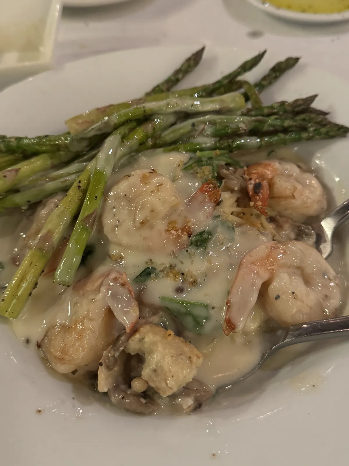 Shrimp and asparagus in a creamy sauce on a plate.