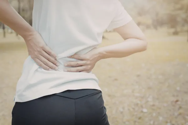 Person holding lower back in pain, transitioning to walking comfortably