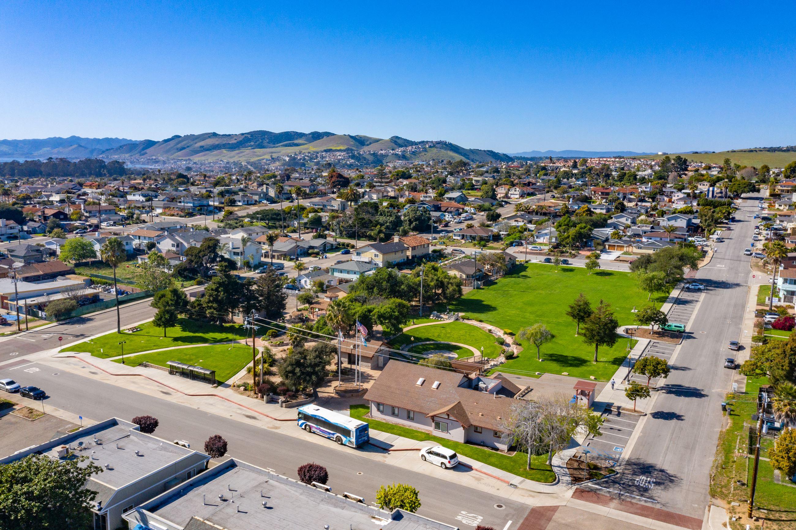 Family-friendly neighborhood in Grover Beach, California, with single-family homes, tree-lined residential streets, a community park, and nearby coastal hills.