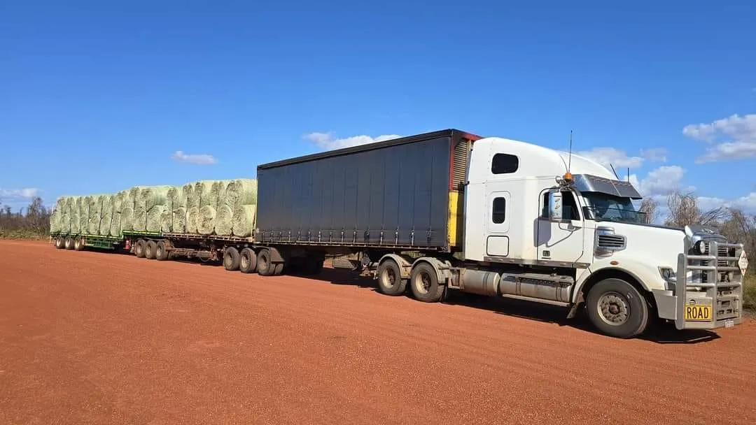 Heavy haul truck transporting hay bales along a rural WA highway for livestock feed supply