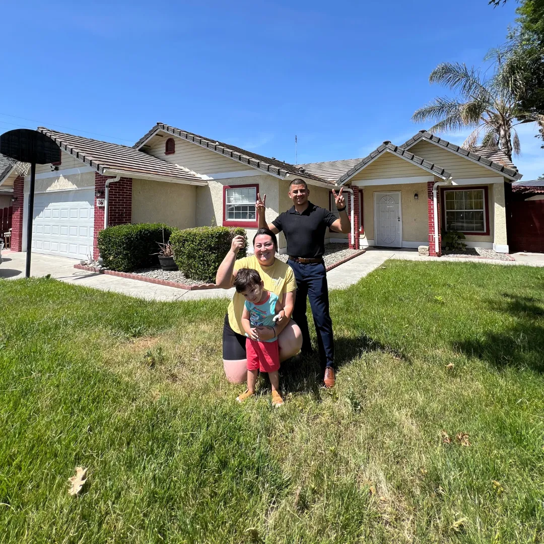 Military family proudly holding keys to their new home and reviewing the home buying guide