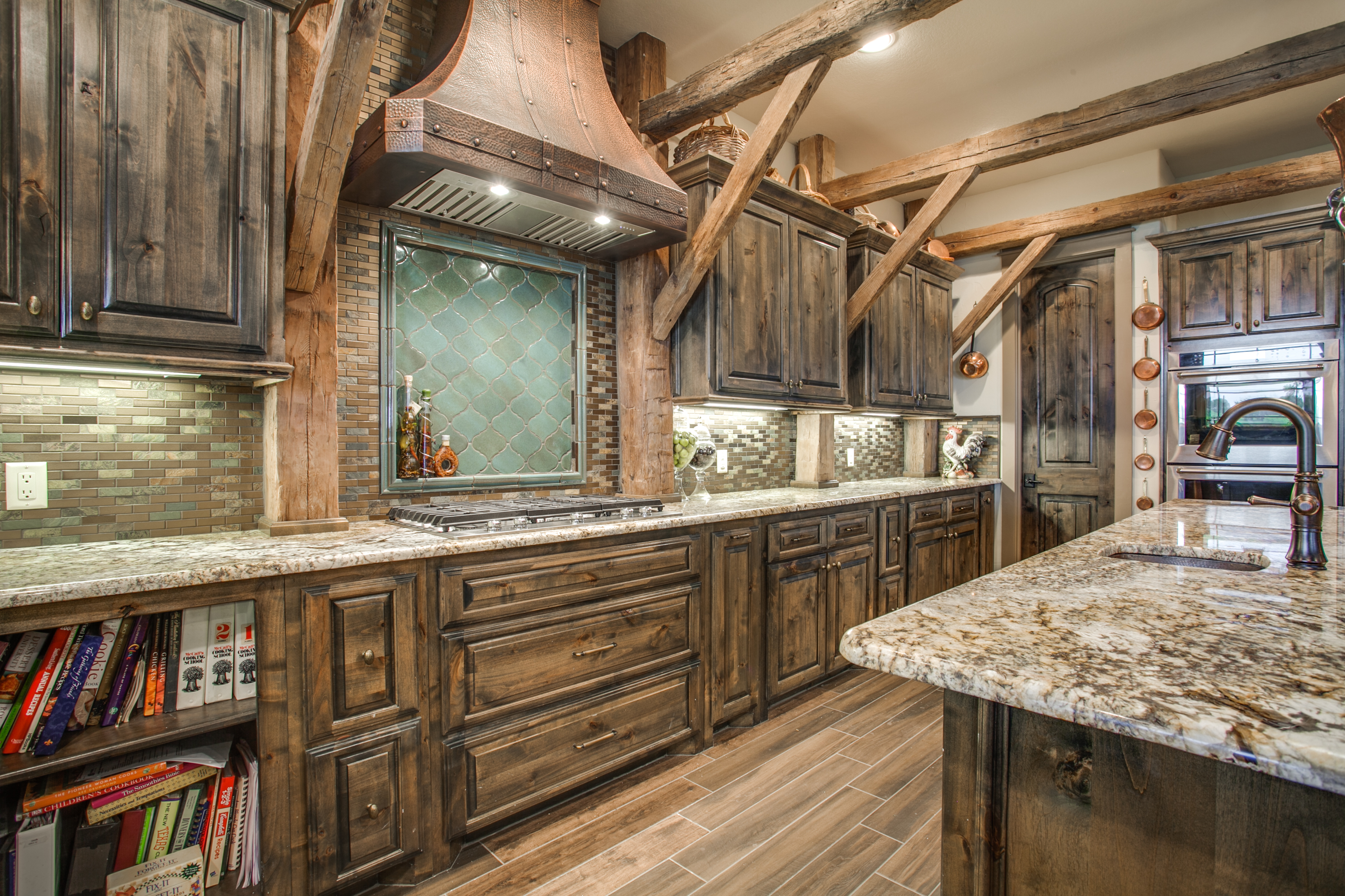 Rustic kitchen interior featuring dark wood cabinetry, granite countertops, and a decorative range hood, emphasizing custom design and functionality for home transformation.