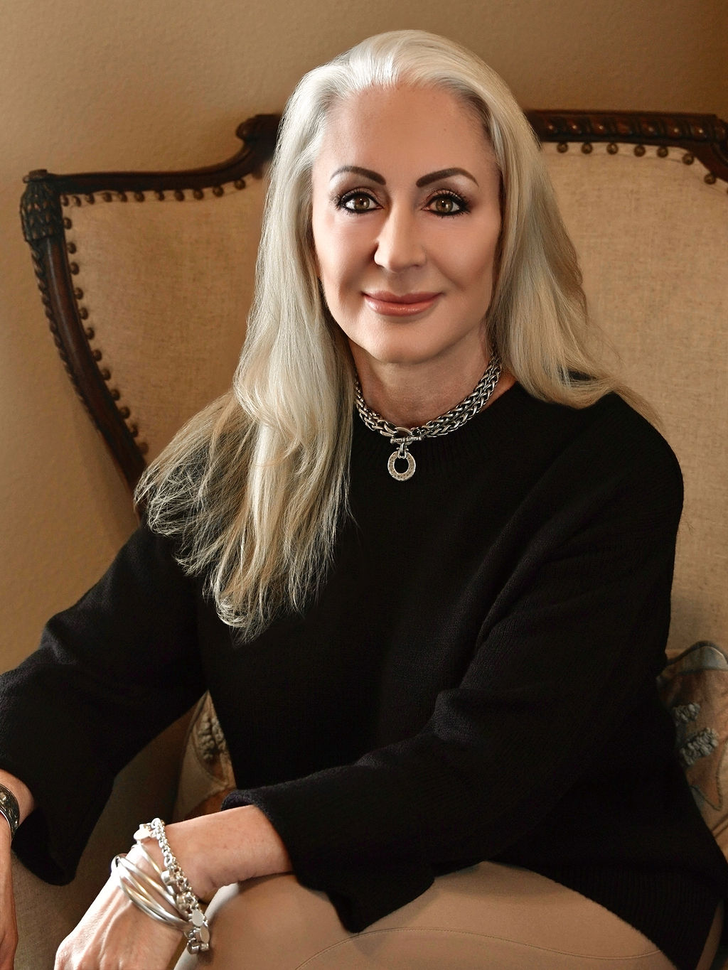 Dawne Holland, interior designer from DHD Interior Designs, seated in a stylish setting, showcasing her elegant style and expertise in creating personalized, timeless spaces.