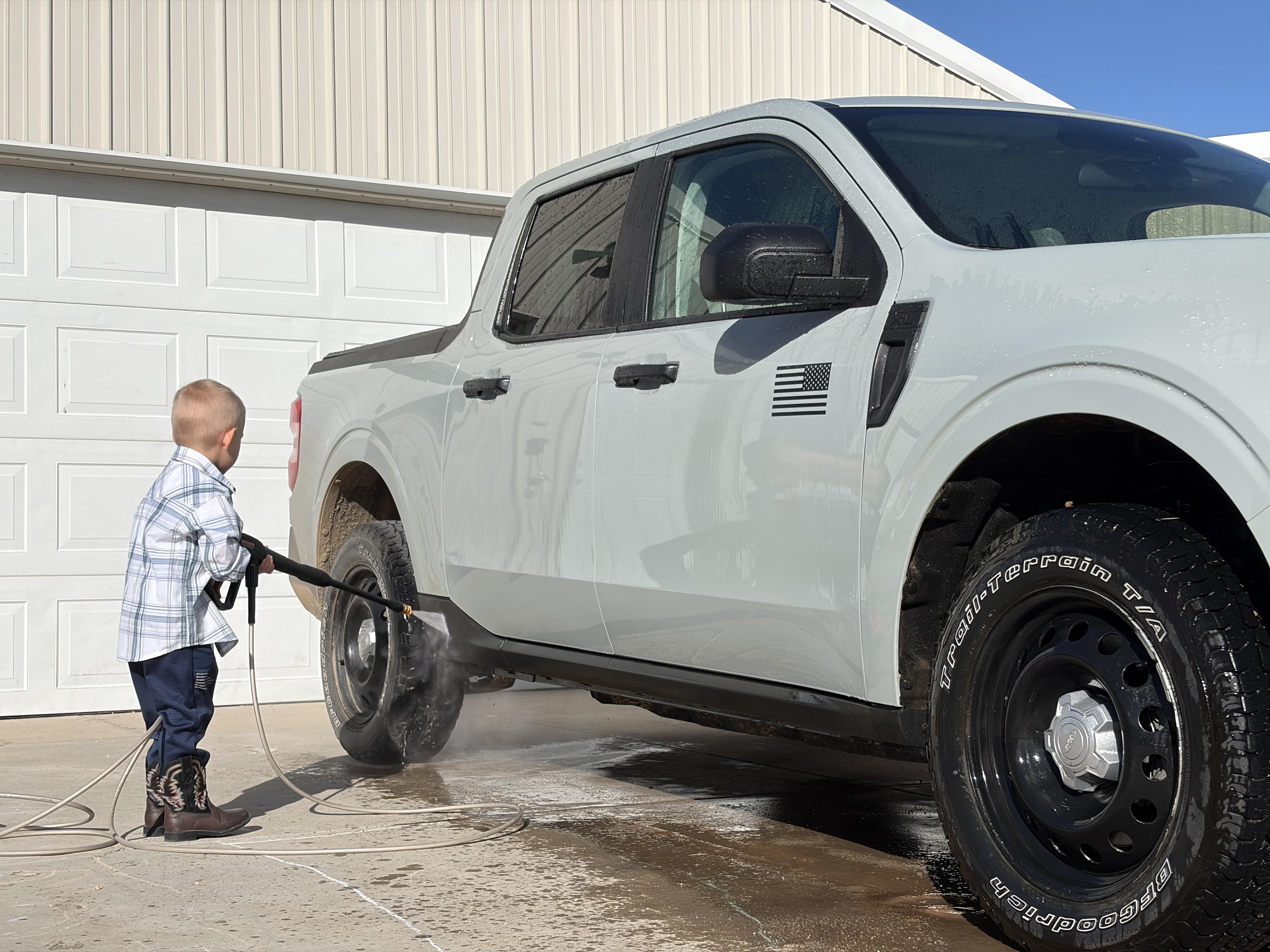 young boy washing a car