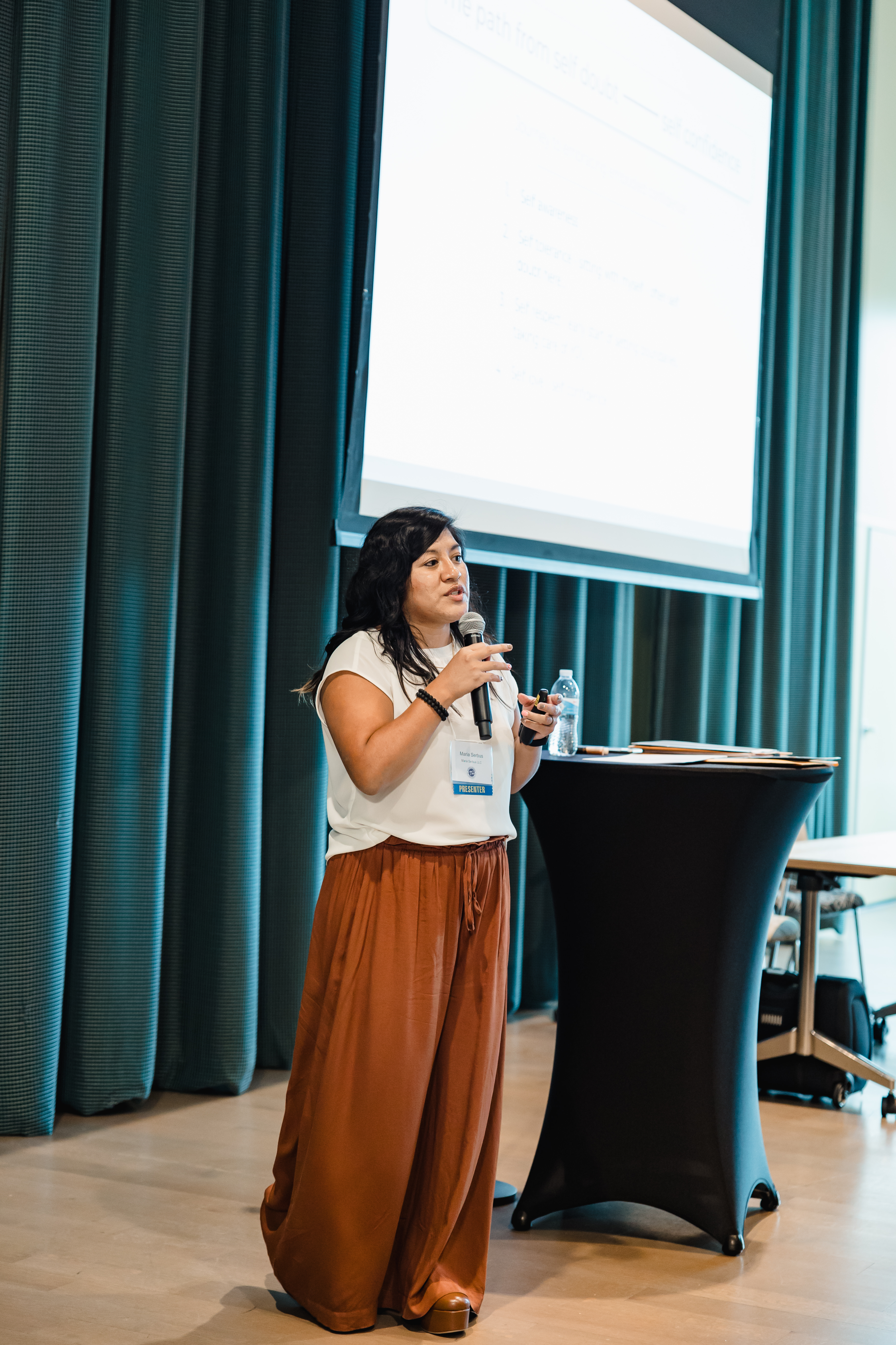Maria Crystene Serbus speaking on stage to a professional audience
