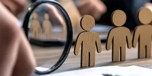 Holzpersonen in einer eihe mit einem Hand mit Lupe