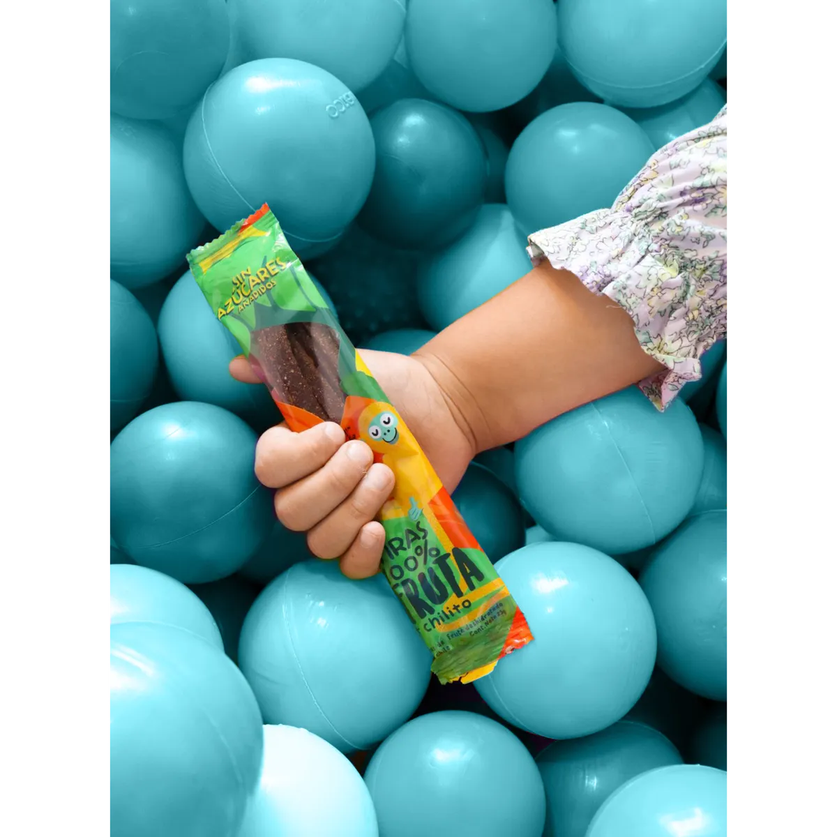 Mano de niña con tiras ¡Ala Terra! en una alberca de pelotas
