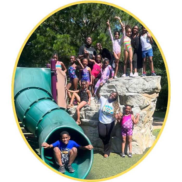 children with teacher playing on slides and smiling