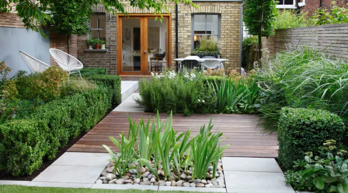 Small, picturesque garden behind an apartment featuring lots of greenery. 