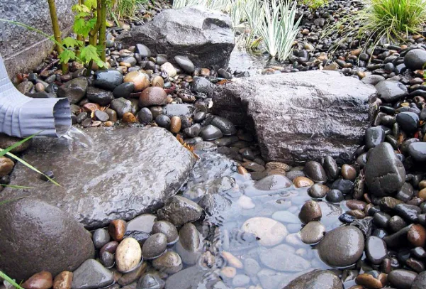 Water draining over decorative rocks in a garden.