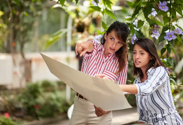 Two landscape designers reviewing plans in a garden.