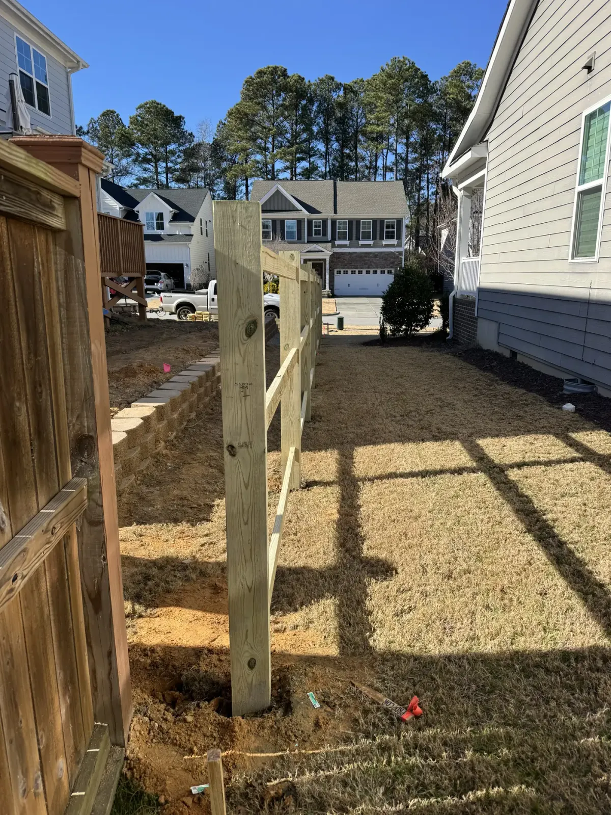 New pressure-treated fence posts and rails replacing an old wood fence in Apex, NC