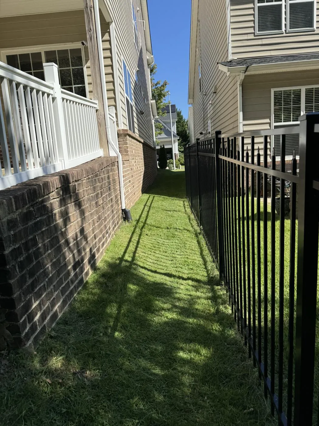 Black aluminum fence along narrow side yard with green grass in Cary, NC