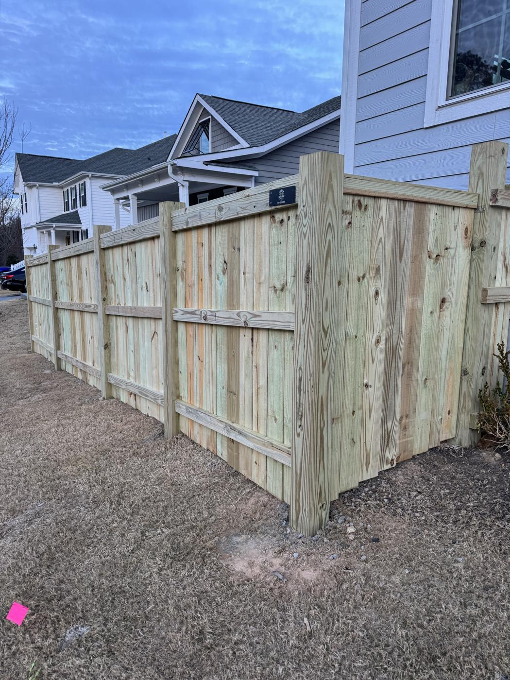 New pressure-treated wood privacy fence with gate along side yard in Apex, NC