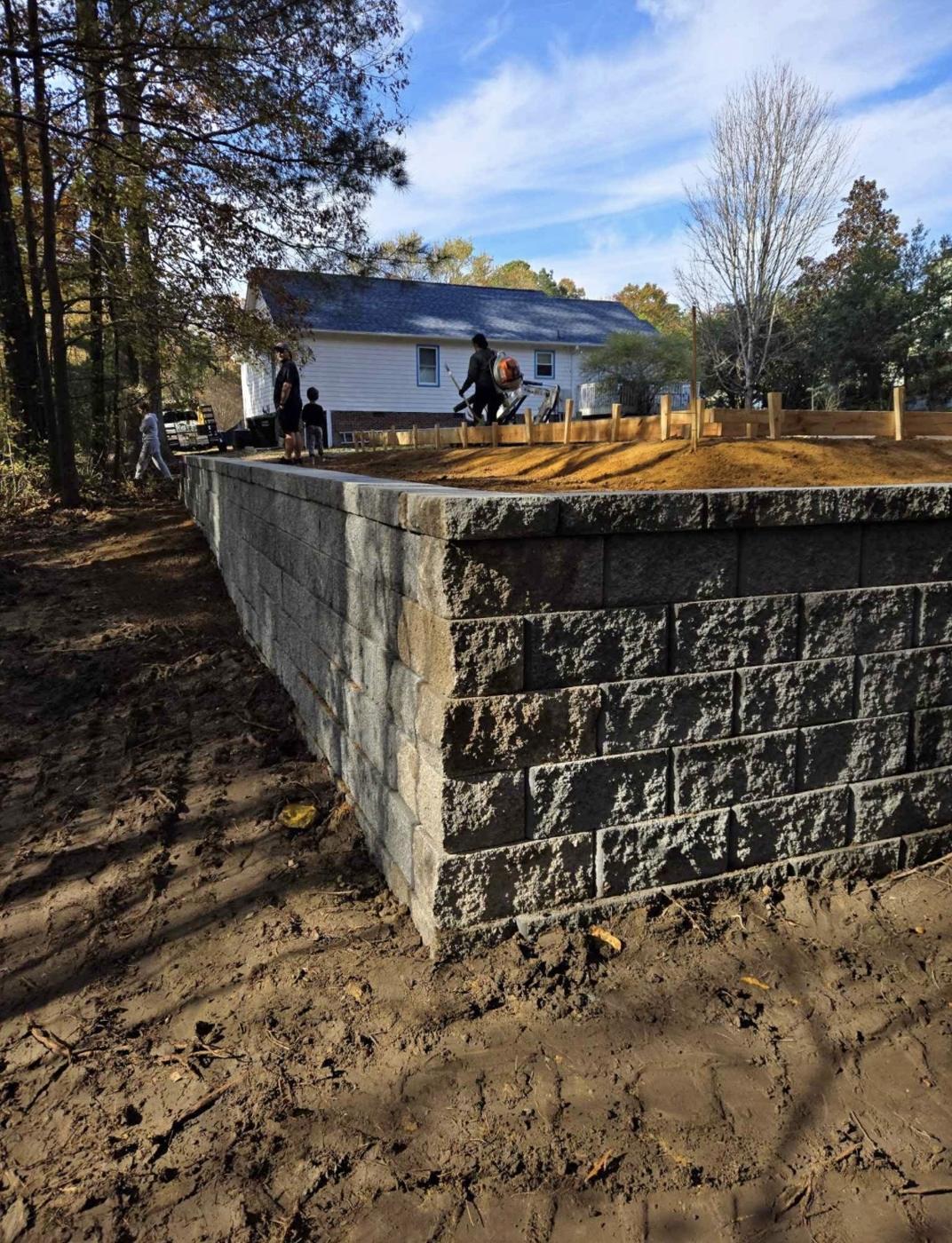 Tall gray block retaining wall corner on a graded backyard in the Triangle, NC