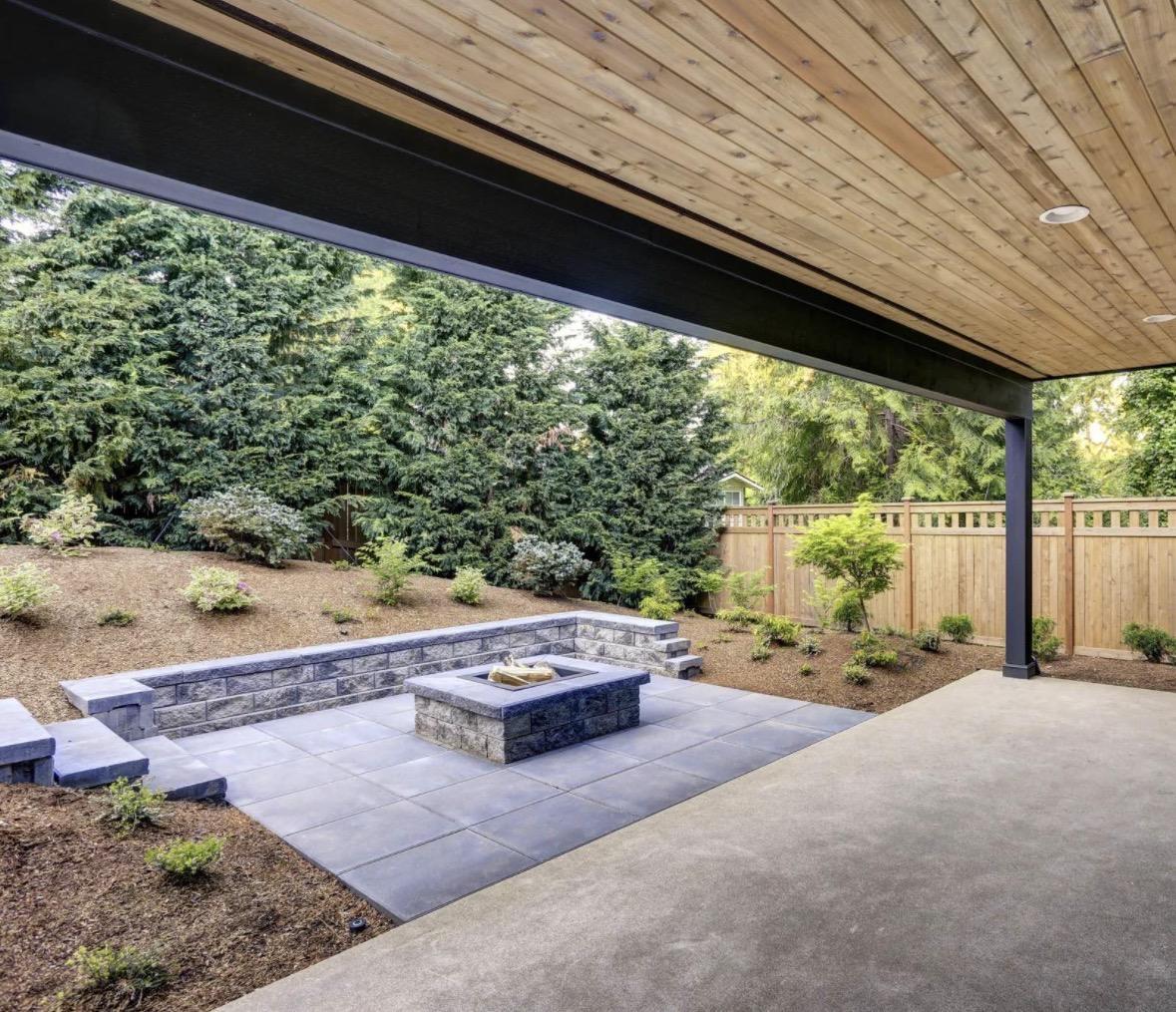 Covered patio with stone seat wall and fire pit near trees in the Triangle, NC