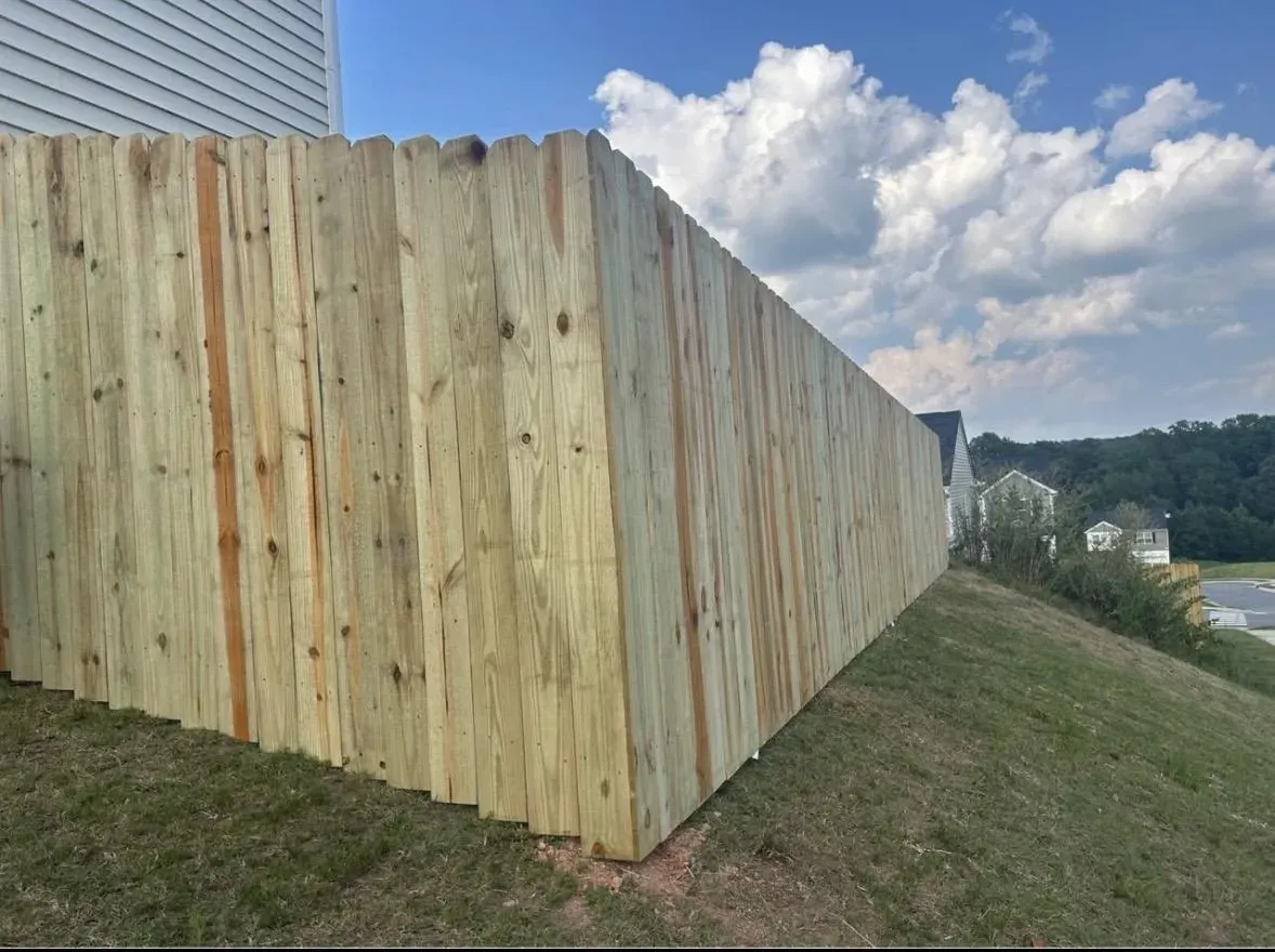 Tall pressure-treated wood privacy fence with dog-ear boards along a sloped backyard in the Triangle, NC