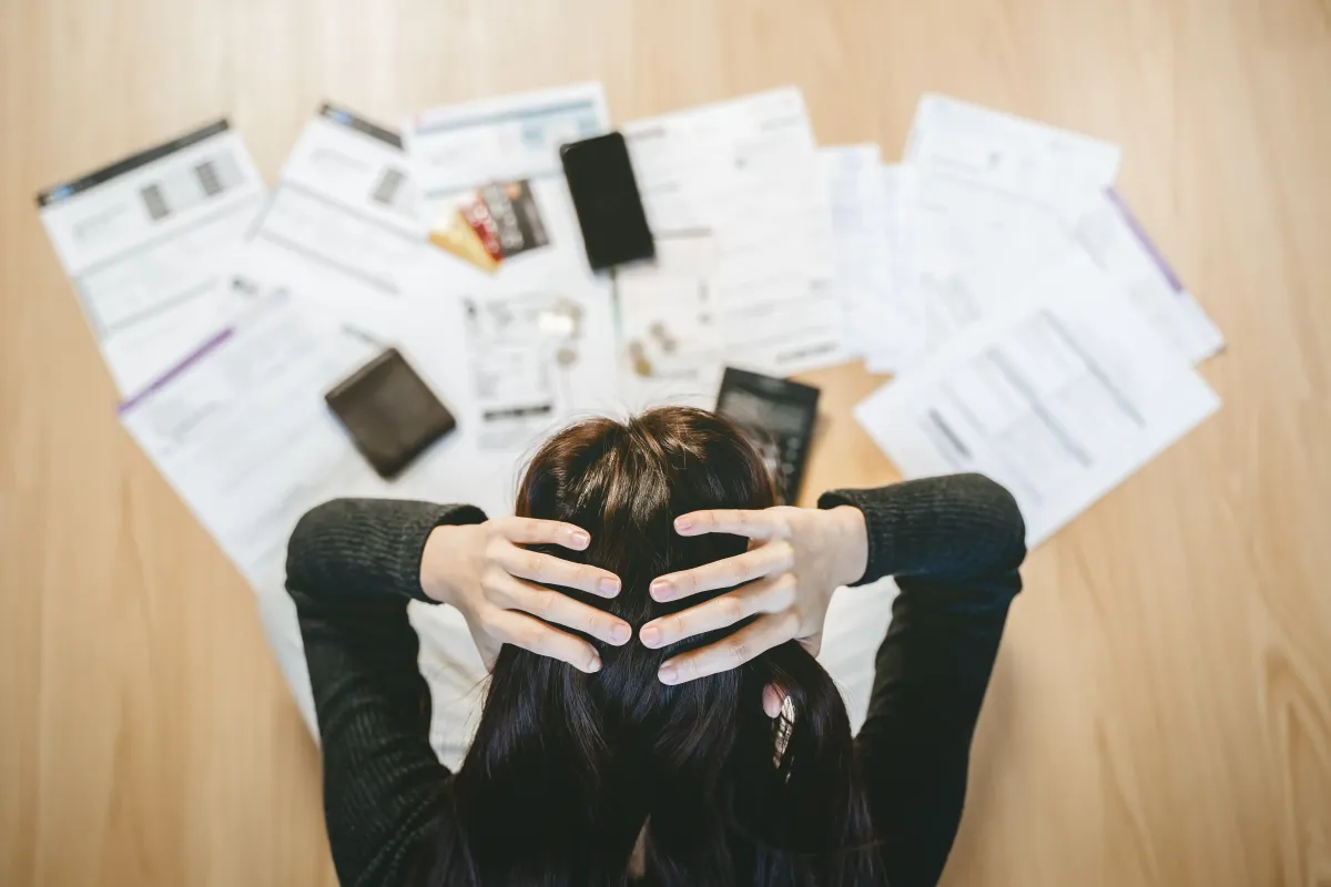 Kate Geissel's client feeling overwhelmed and stressed by a large pile of tax and accounting paperwork.