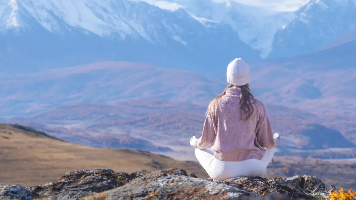 woman sat alone on mountain looking out 