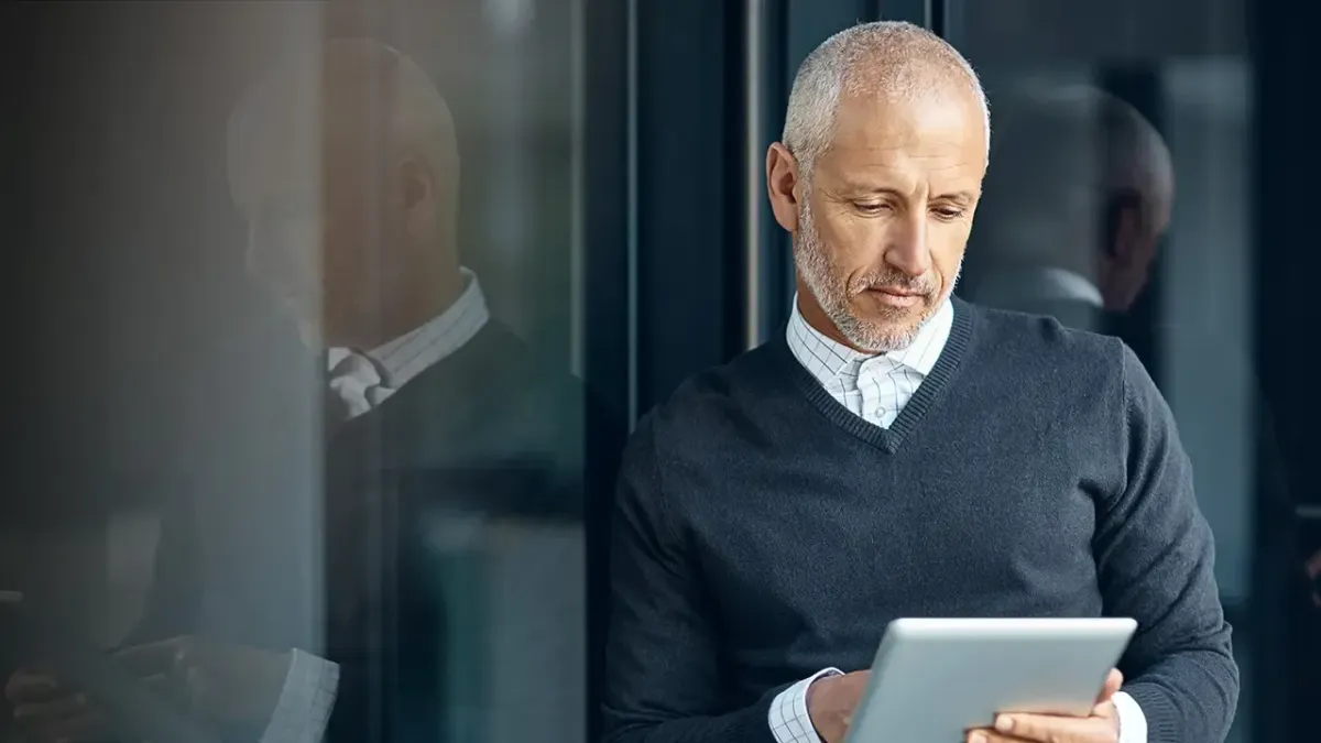 Male healthcare practitioner looking at patient data on tablet.