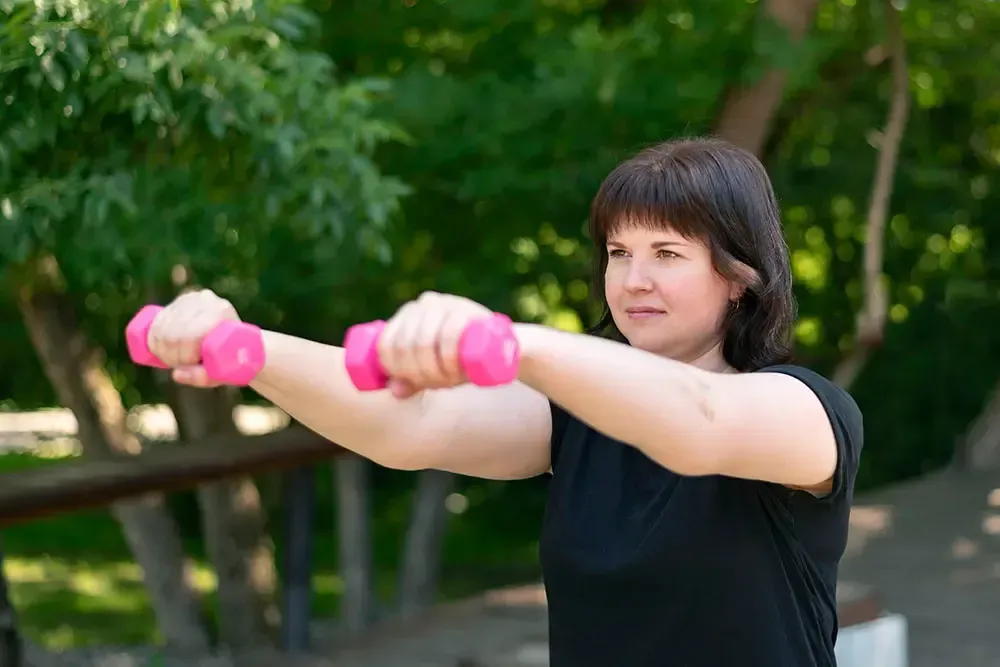 Female lifting small weights to build strength and lose weight.