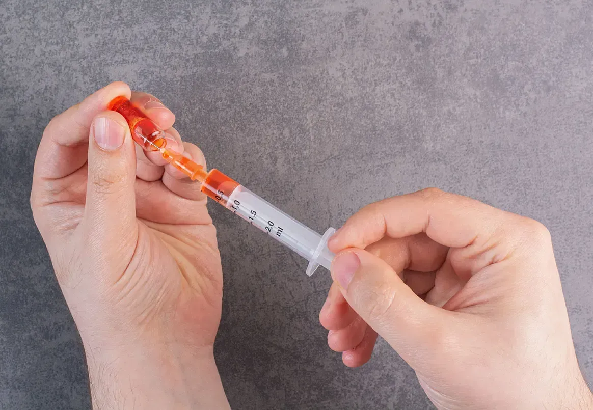 Practitioner preparing a syringe for a vitamin B12 injection.