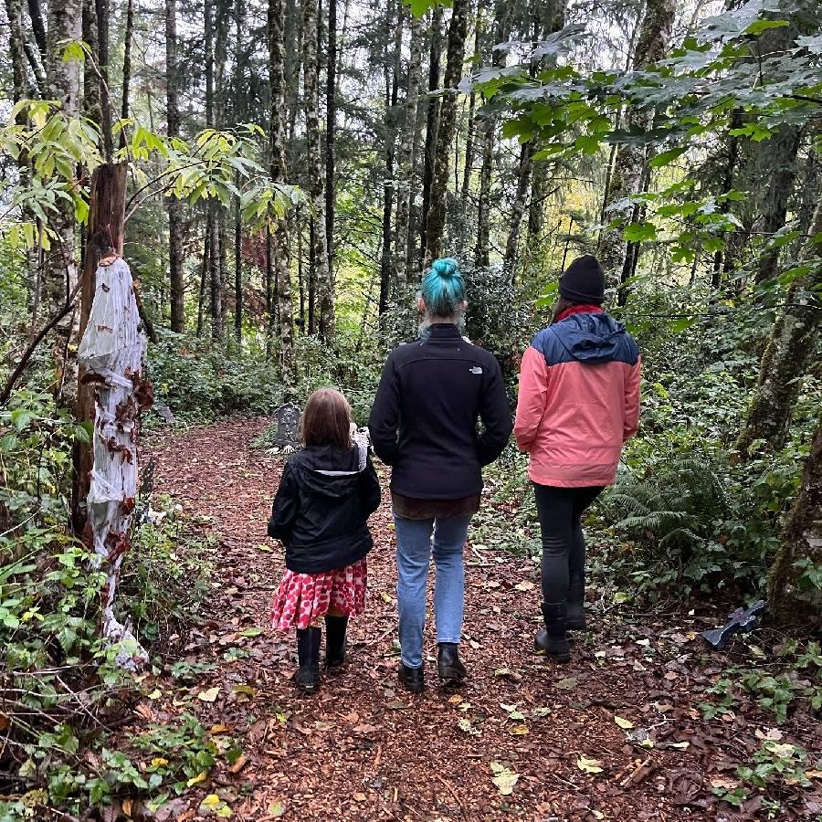 Three people walking through the spooky trail.