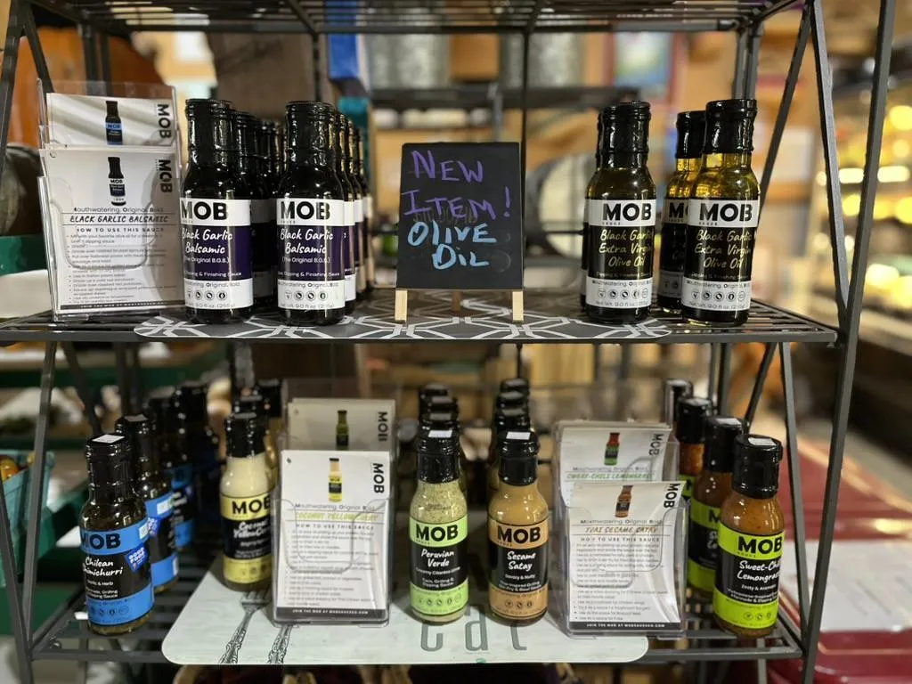 Farm stand shelf with a variety of bottles of MOB Sauce products.
