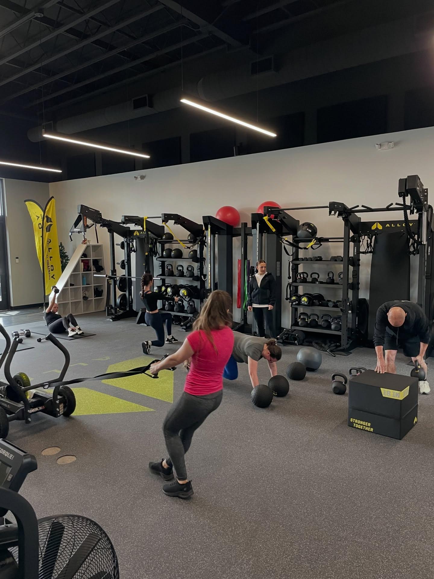 Small group personal training session at Alloy Personal Training Cedar Hills Crossing with adults performing functional strength exercises under the guidance of certified personal trainers.